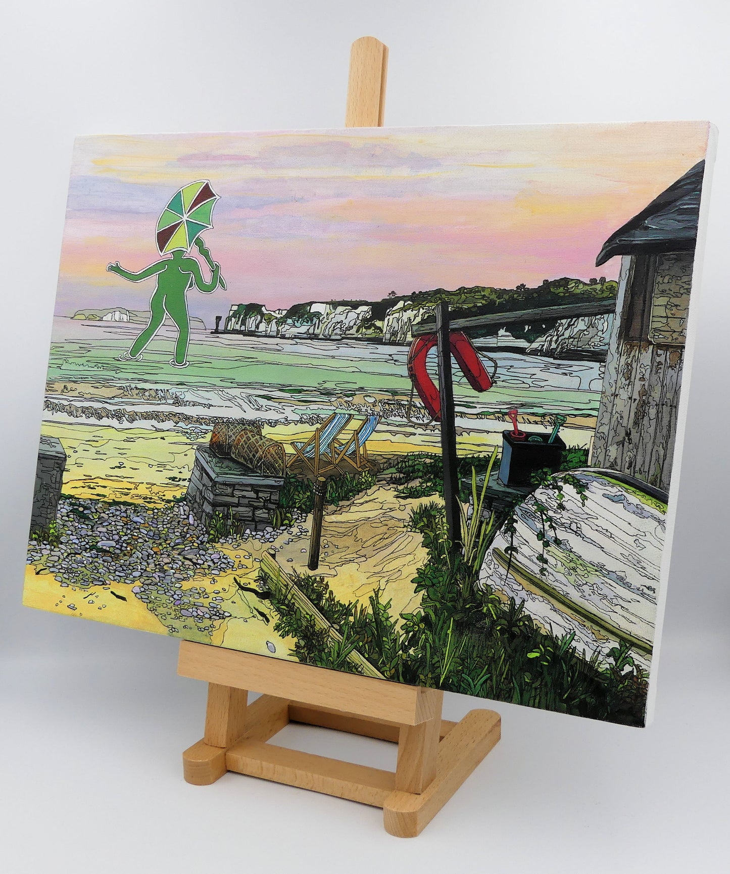 Image of the original painting 'Mrs Cerne Abbas Giant Visits Studland' by Nick Dale on a small easel. The painting imagines the Cerne Abbas Giant's wife visiting the seaside at Studland Beach; with Old Harry Rocks and the Isle of Wight in the distance.