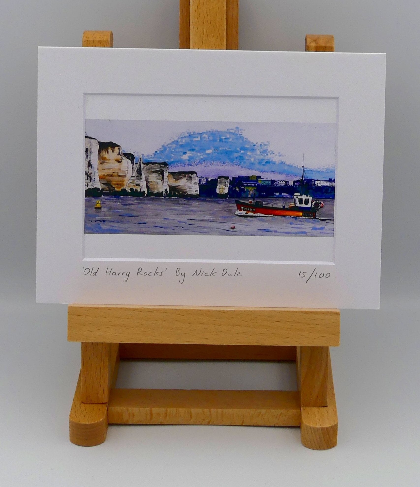 Image of Small Art Print featuring a copy of a detail of the painting 'Old Harry Rocks' by Nick Dale. The print depicts the chalk formations located at Handfast Point, south of Studland Bay; as viewed from Peveril Point, Swanage. Also depicted is a small fishing boat returning to Swanage and the Bournemouth skyline beyond the cliffs. The print is situated on a small easel.