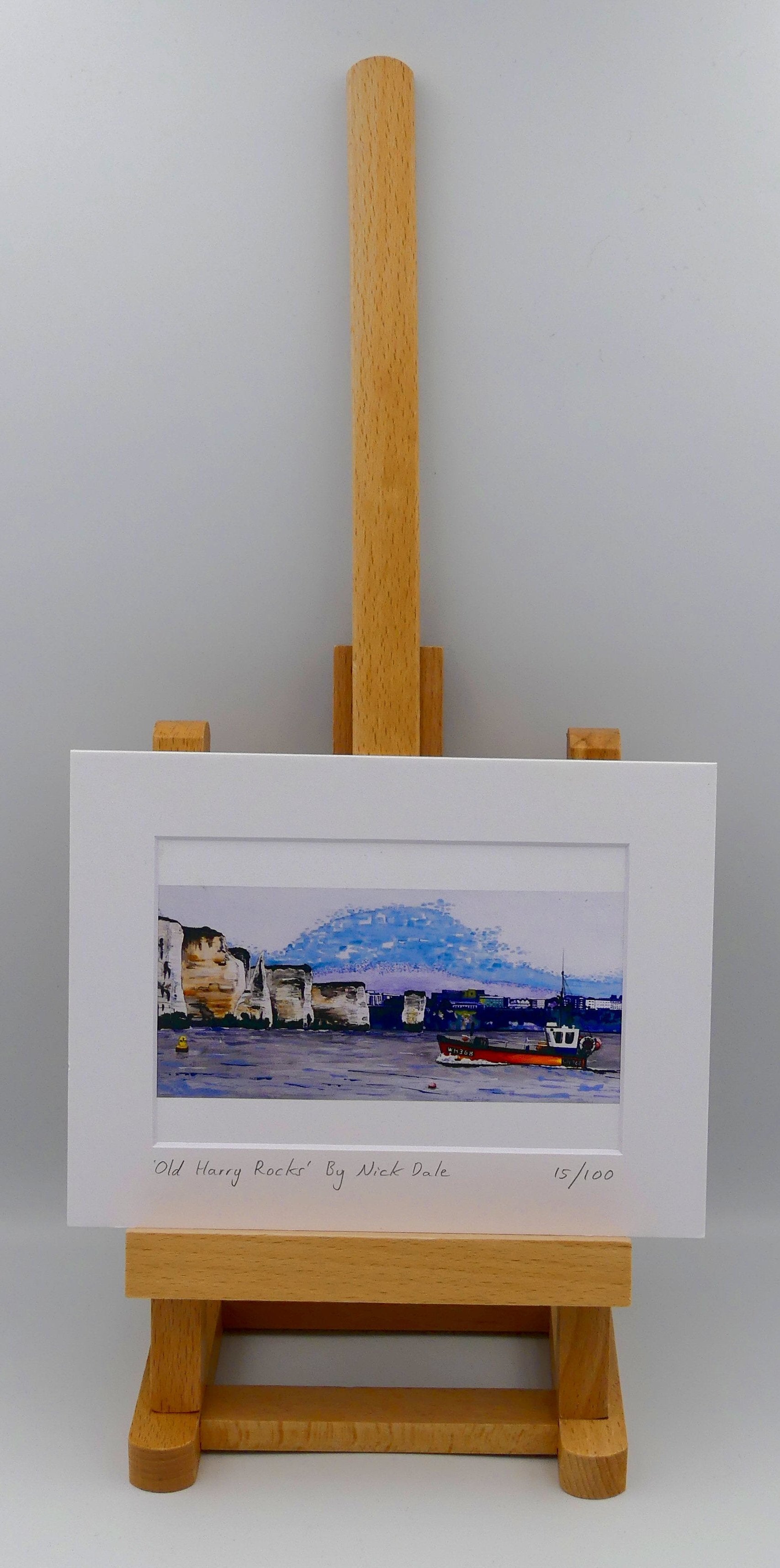 Image of Small Art Print featuring a copy of a detail of the painting 'Old Harry Rocks' by Nick Dale. The print depicts the chalk formations located at Handfast Point, south of Studland Bay; as viewed from Peveril Point, Swanage. Also depicted is a small fishing boat returning to Swanage and the Bournemouth skyline beyond the cliffs. The print is situated on a small easel.