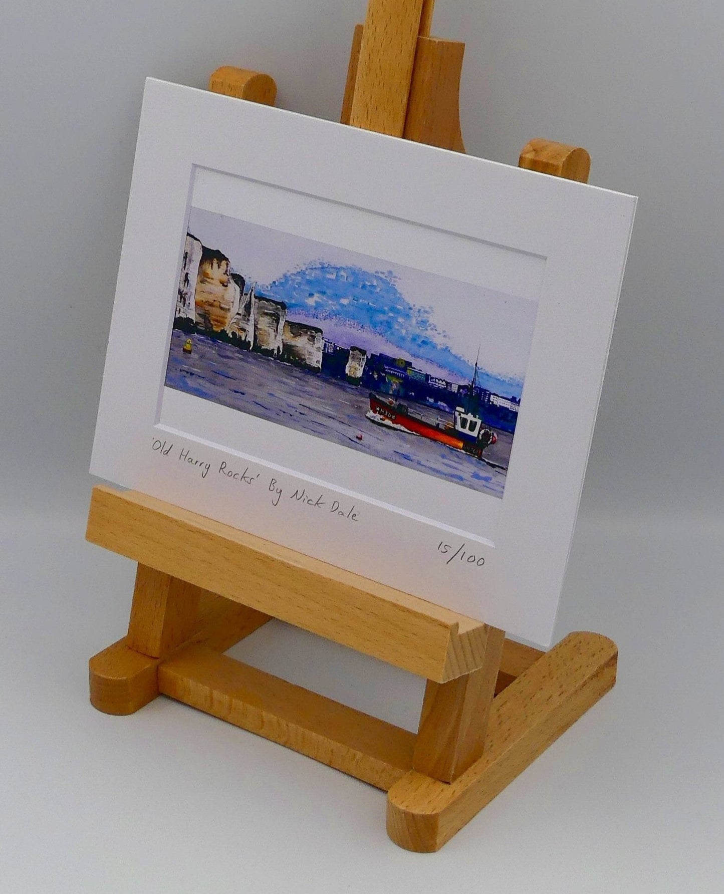 Image of Small Art Print featuring a copy of a detail of the painting 'Old Harry Rocks' by Nick Dale. The print depicts the chalk formations located at Handfast Point, south of Studland Bay; as viewed from Peveril Point, Swanage. Also depicted is a small fishing boat returning to Swanage and the Bournemouth skyline beyond the cliffs. The print is situated on a small easel.