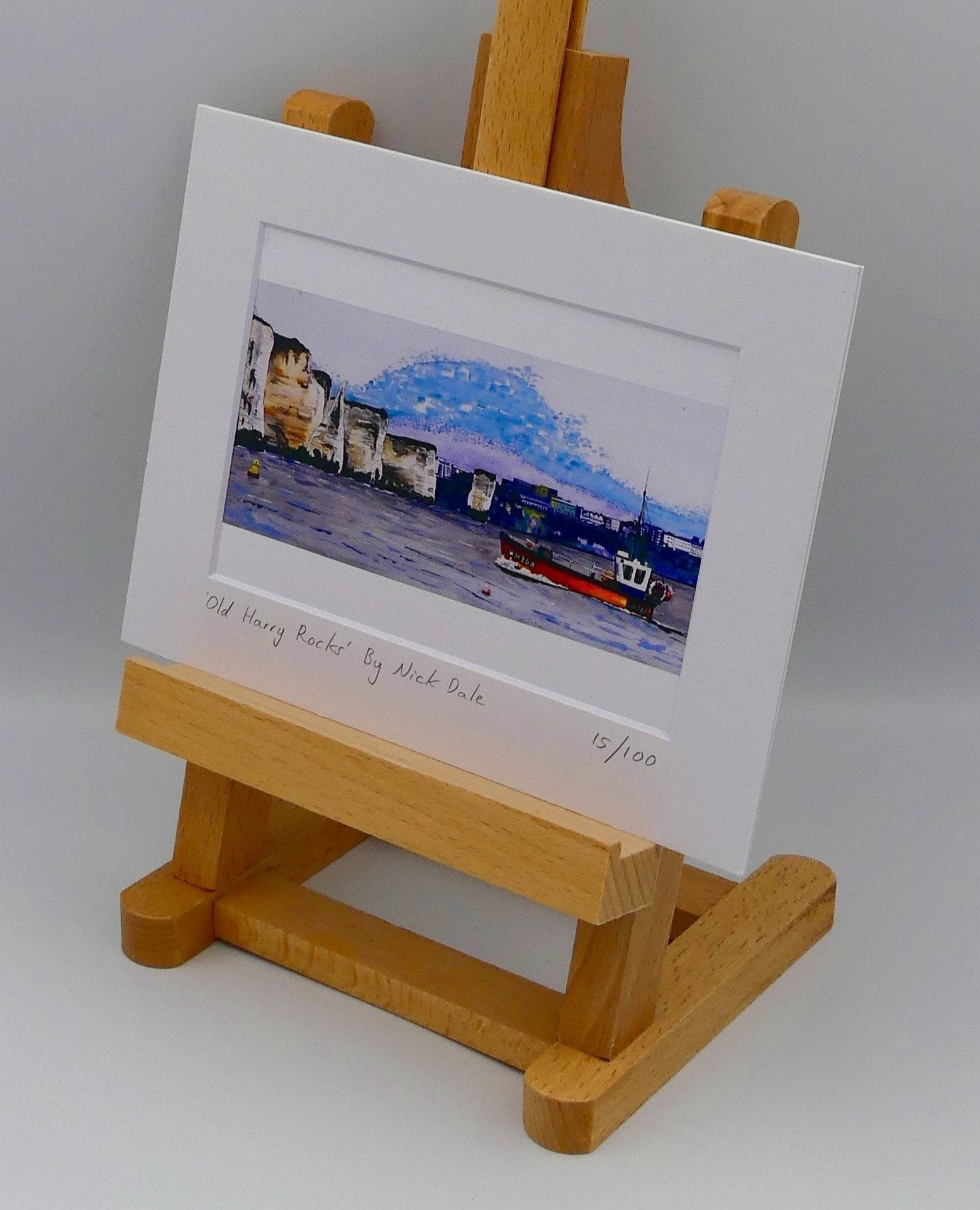 Image of Small Art Print featuring a copy of a detail of the painting 'Old Harry Rocks' by Nick Dale. The print depicts the chalk formations located at Handfast Point, south of Studland Bay; as viewed from Peveril Point, Swanage. Also depicted is a small fishing boat returning to Swanage and the Bournemouth skyline beyond the cliffs. The print is situated on a small easel.