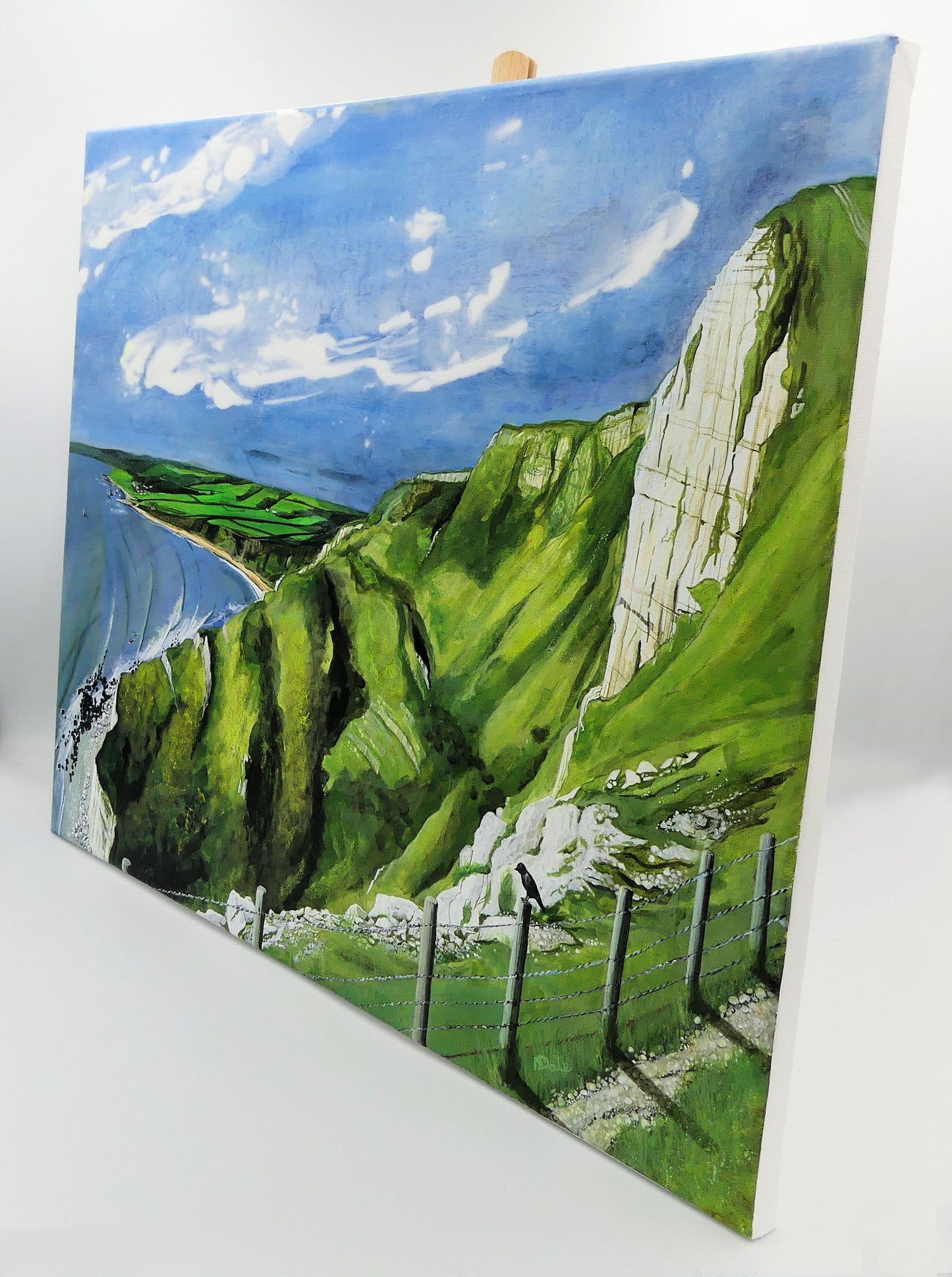 Image of the original painting 'Ringstead Bay From The White Nothe' by Nick Dale on a small easel. The painting depicts a view along the Jurassic Coast from the White Nothe chalk headland east of Ringstead Bay. The view looks west over the bay to the village of Ringstead & beyond.