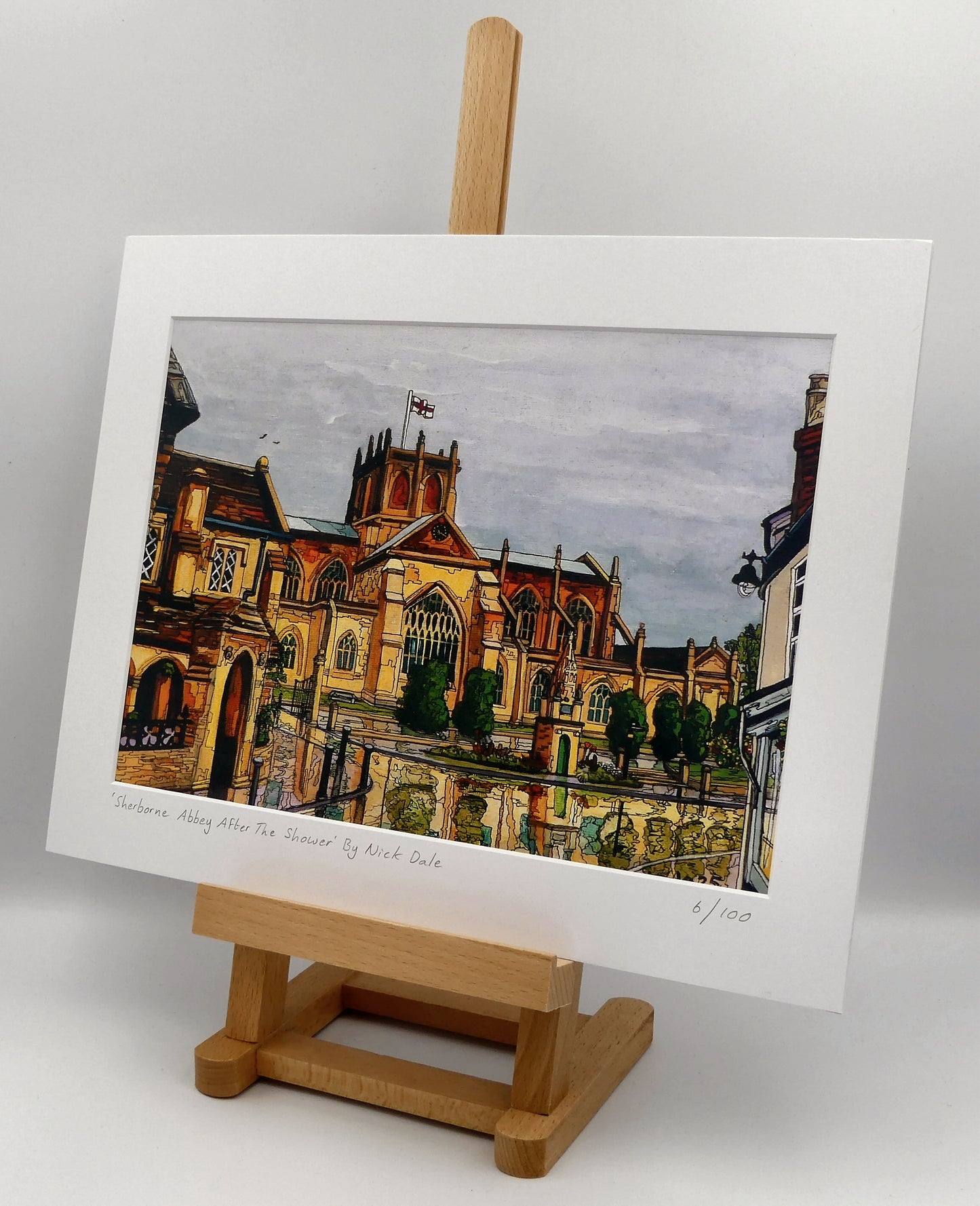 Image of a Medium Art Print featuring a copy of the painting 'Sherborne Abbey After The Shower' by Nick Dale. The print depicts a view of Sherborne Abbey (also known as the Abbey Church of St. Mary the Virgin), in Sherborne, Dorset. On the left hand side can be seen St Johns' Almshouse.
The print is situated on a small easel.