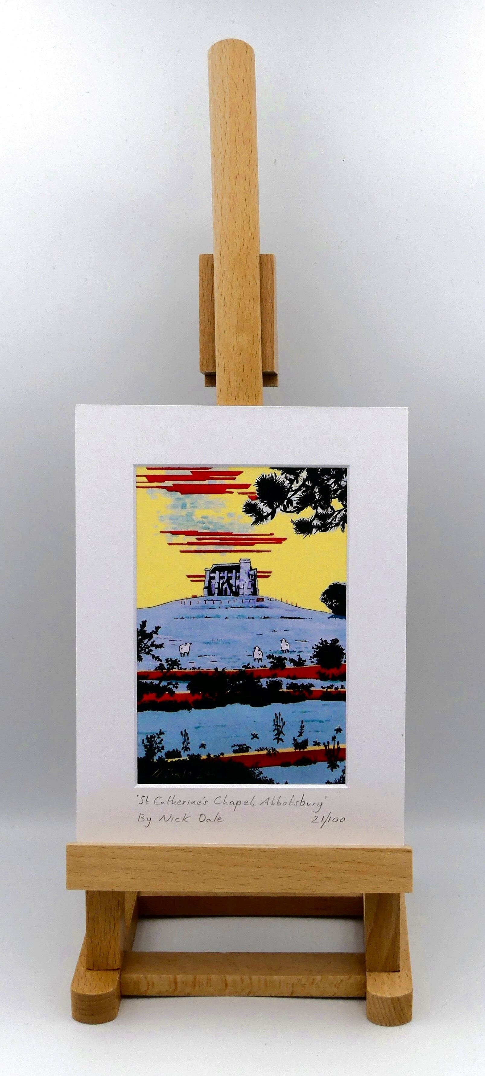 Image of Small Art Print featuring a copy of the painting 'St Catherine's Chapel, Abbotsbury' by Nick Dale. The print depicts the Medieval St Catherine's Chapel which is positioned overlooking the village of Abbotsbury. The print is situated on a small easel.