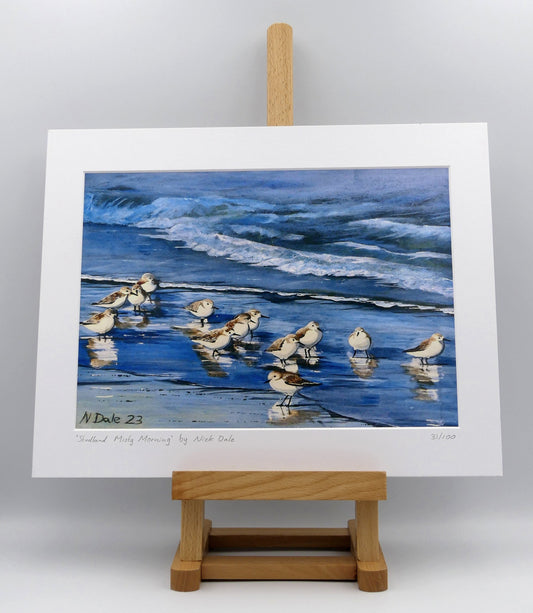 Image of a Medium Art Print featuring a copy of the painting 'Studland Misty Morning' by Nick Dale. The print depicts Dunlins on Studland Beach (Dorset) on a crisp and misty morning. The print is situated on a small easel.