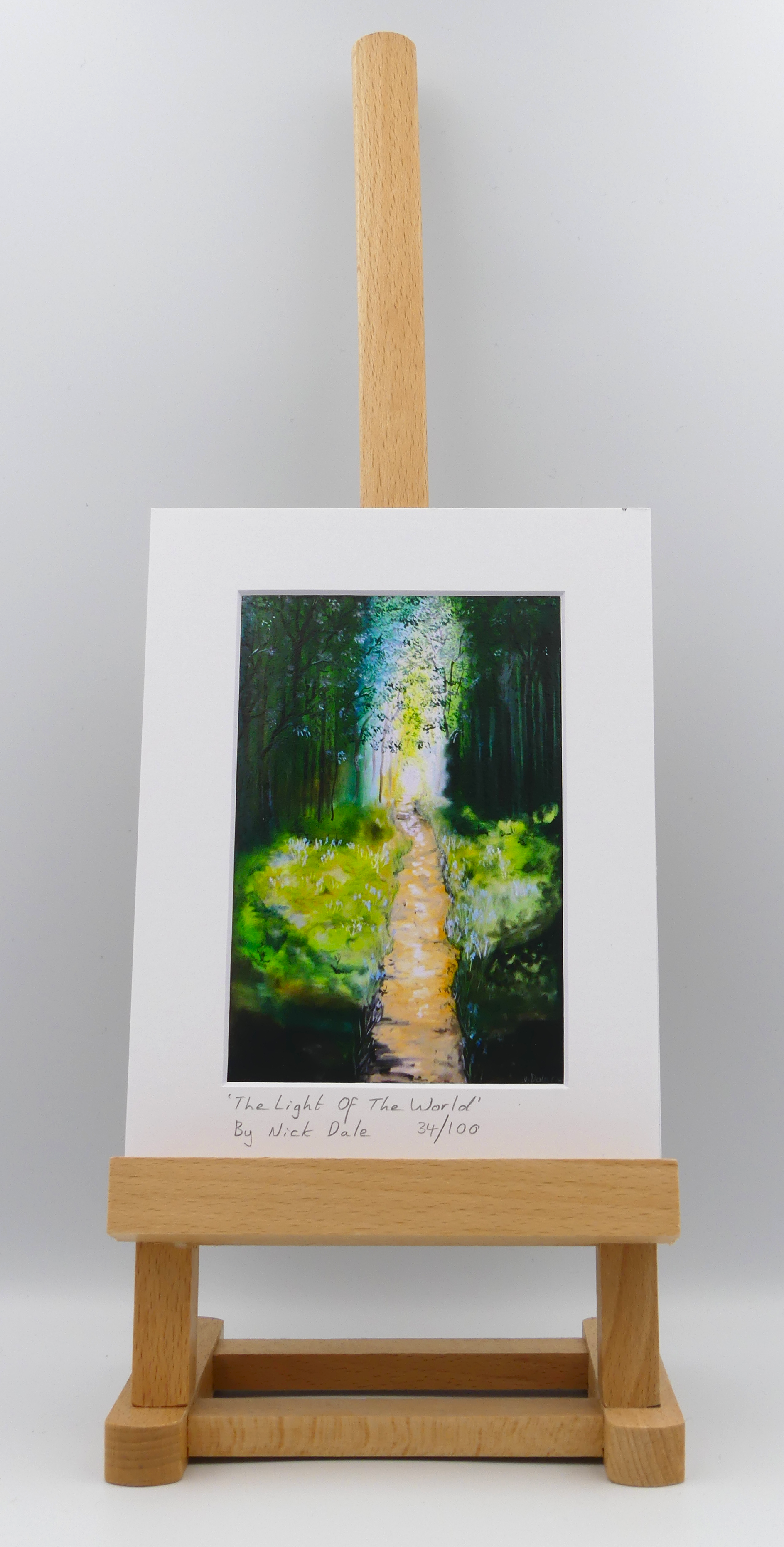 Image of a Small Art Print featuring a copy of the painting 'The Light of the World' by Nick Dale. The print depicts a woodland path at Westonbirt Arboretum (near the town of Tetbury in Gloucestershire) illuminated by the sunlight streaming through the trees. The print is situated on a small easel.
