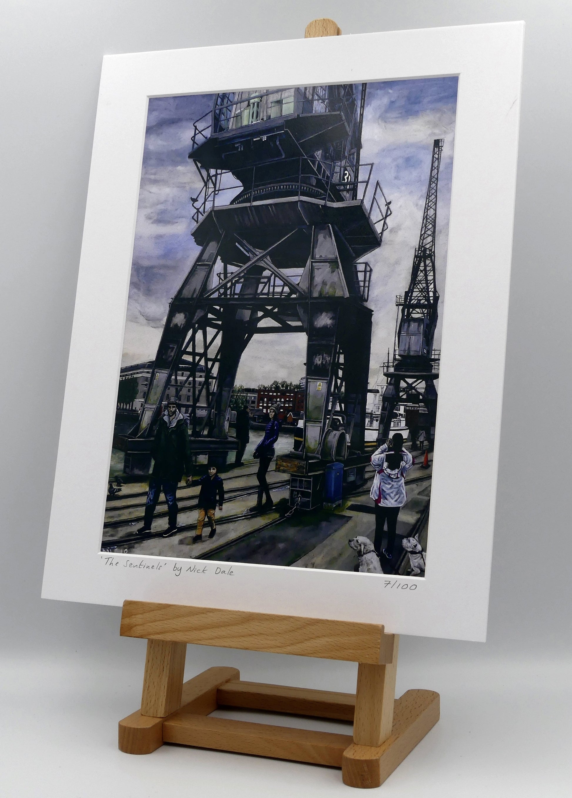 Image of a Medium Art Print featuring a copy of the painting 'The Sentinels' by Nick Dale. The print depicts the iconic tower cranes of Bristol Docks and the classic ship MV Balmoral beyond them. The print is situated on a small easel.