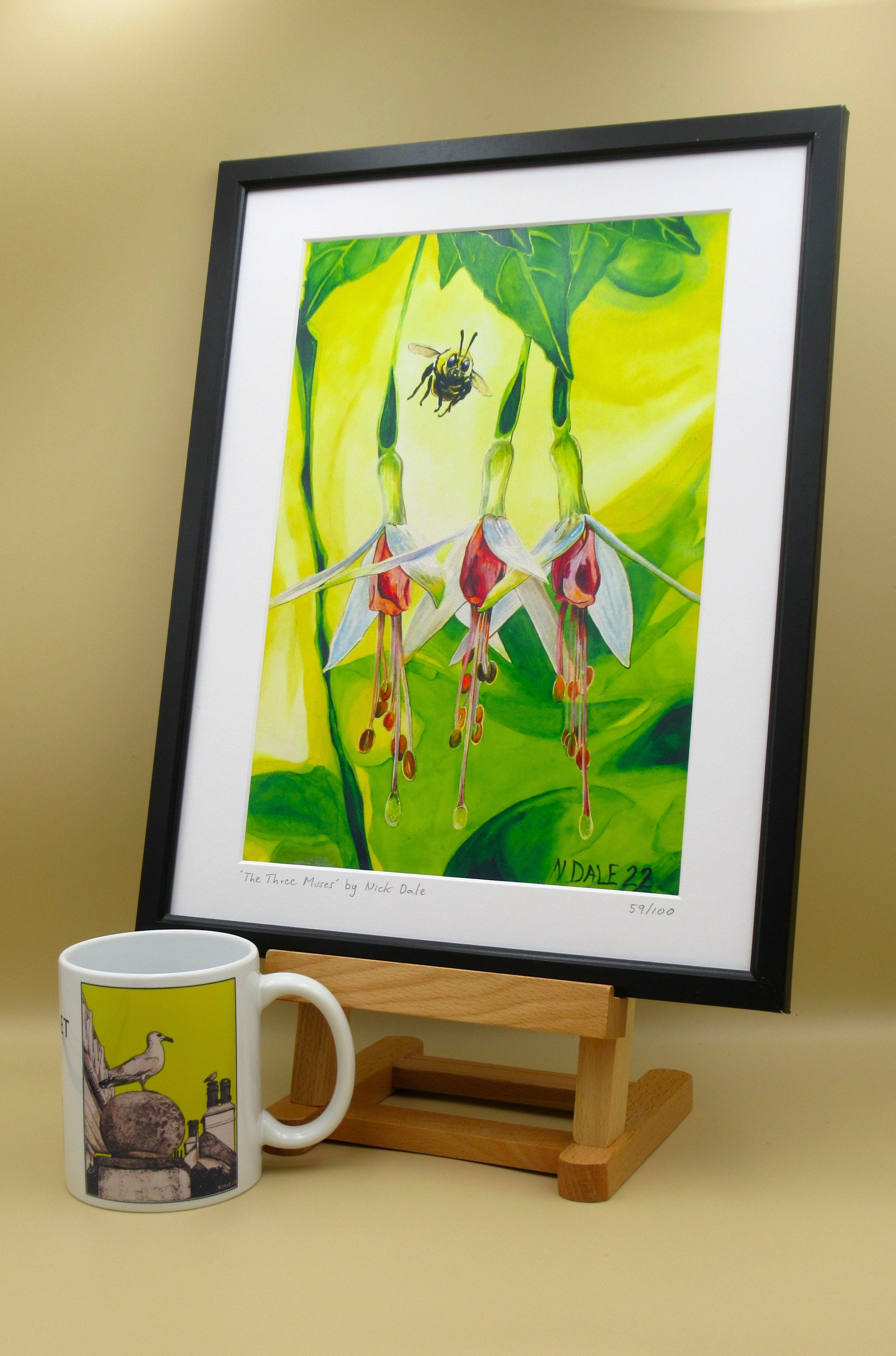Image of a Medium Art Print featuring a copy of the painting 'The Three Muses' by Nick Dale. The print depicts a close-up view of a bee approaching its prize. But which will it choose? The print is situated in a black frame next to a mug.