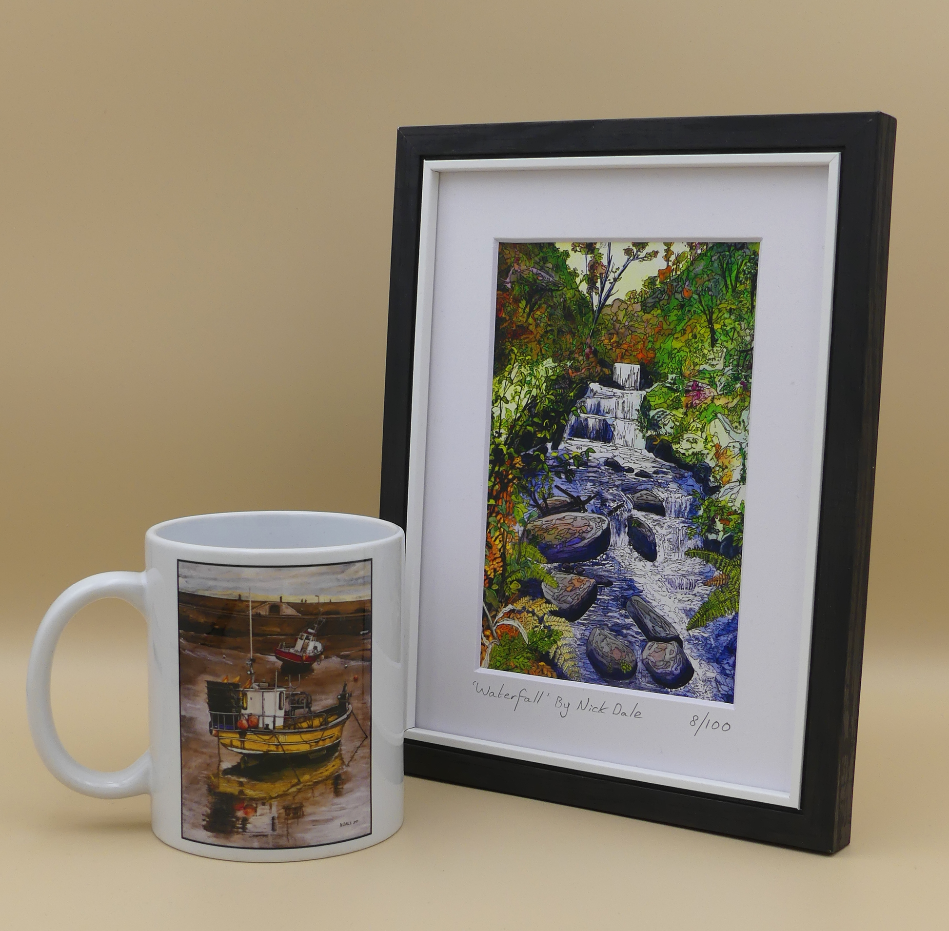 Image of a Small Art Print featuring a copy of the painting 'Waterfall' by Nick Dale. The scene depicts the Hoar Oak Waterfall on the Hoar Oak Water moorland tributary of the East Lyn River at the famous National Trust site of Watersmeet House, Lynmouth, Devon. The print is situated in a black frame next to a mug.