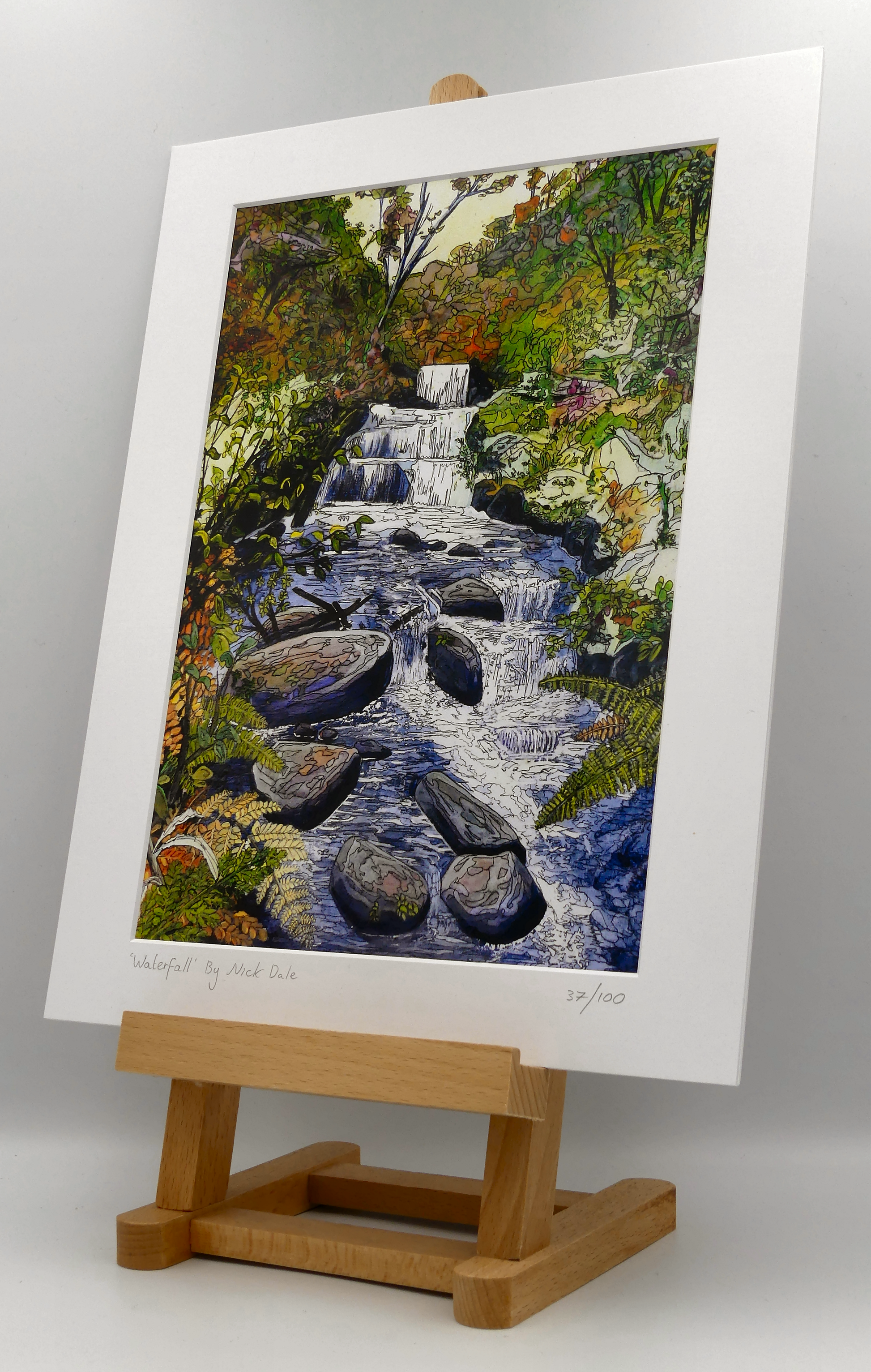 Image of a Medium Art Print featuring a copy of the painting 'Waterfall' by Nick Dale. The scene depicts the Hoar Oak Waterfall on the Hoar Oak Water moorland tributary of the East Lyn River at the famous National Trust site of Watersmeet House, Lynmouth, Devon. The print is situated on a small easel.