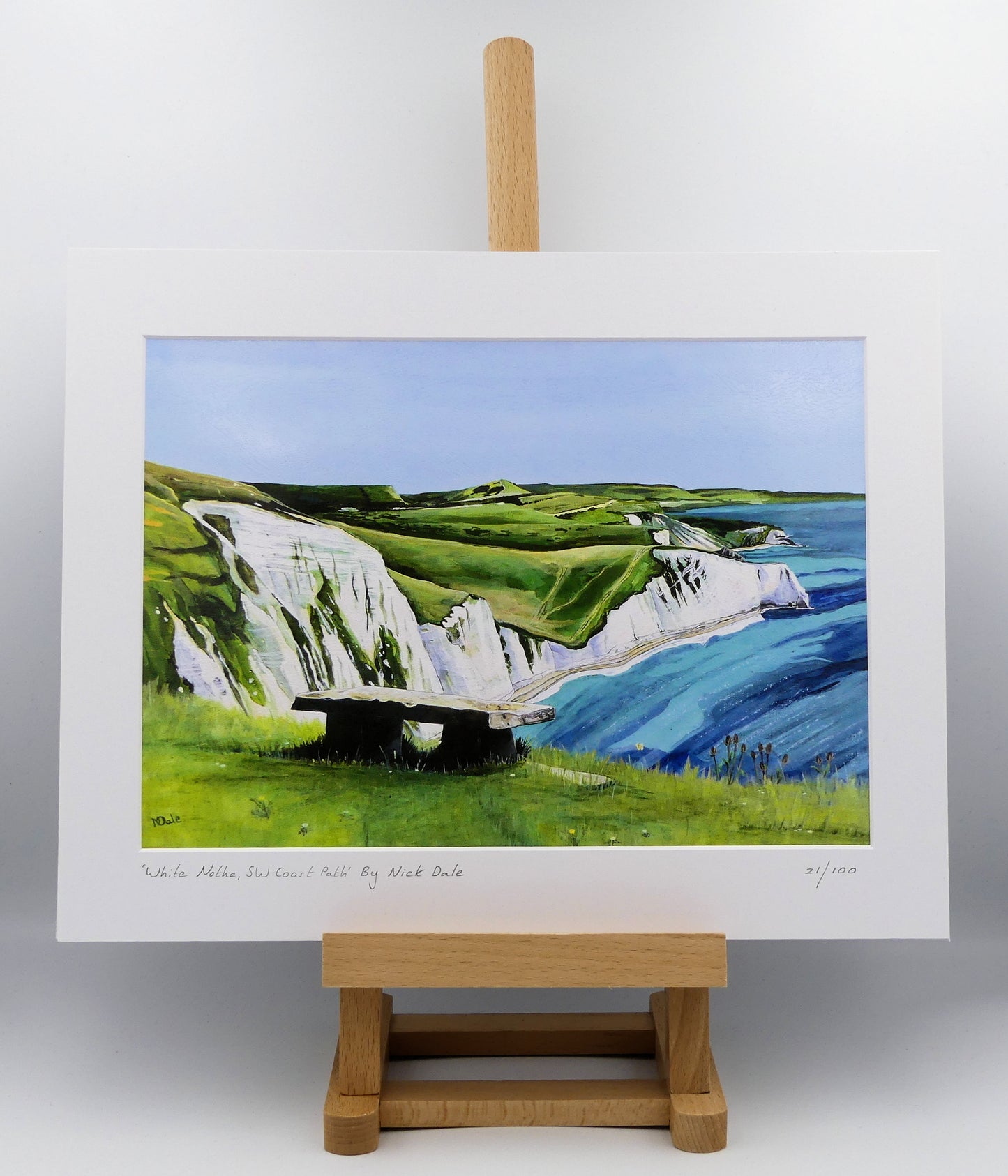 Image of a Medium Art Print featuring a copy of the painting 'White Nothe, SW Coast Path' by Nick Dale. The print depicts a view along the Jurassic Coast from the White Nothe chalk headland east of Ringstead Bay. The view looks east over Bat's Head, Swyre Head and Durdle Door to St Oswald's Bay & beyond. The print is situated on a small easel.