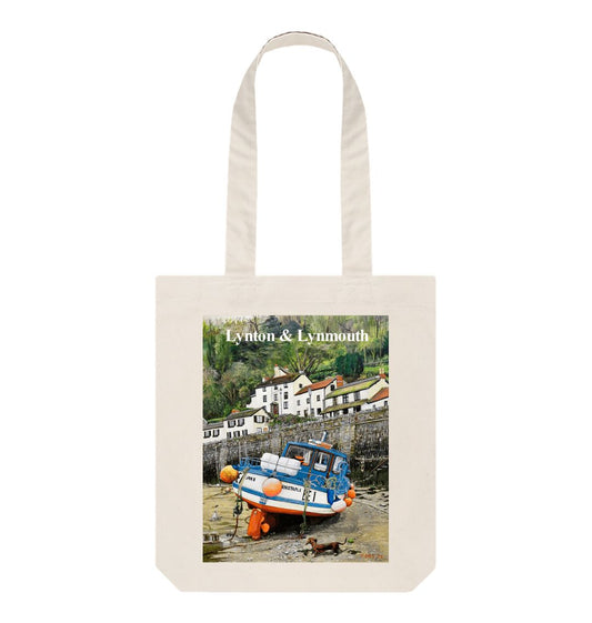 Image of a Natural Tote Bag featuring a copy of the painting 'Lynmouth At Lowest Tide' by Nick Dale, with the words 'Lynton & Lynmouth' written across the top. The bag depicts an unusual perspective on the picturesque harbour of Lynmouth (Devon), as seen from the floor of the harbour at low tide. Behind the fishing boat can be seen the characterful harbourside buildings.