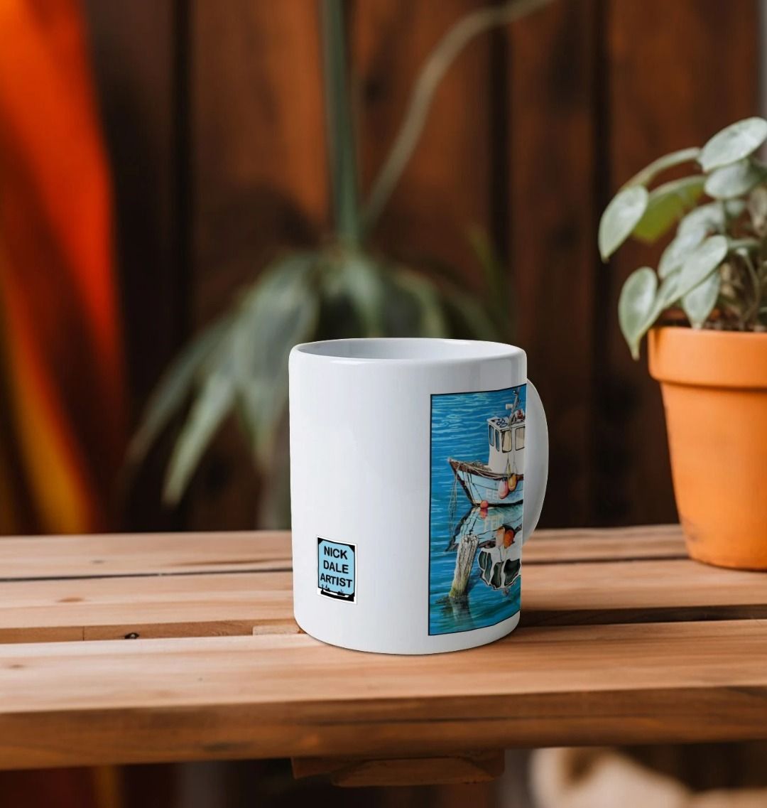 Image of a White Mug on a shelf featuring a copy of the painting 'God's Own 99 Flake Pierces The Veil' by Nick Dale. Image also shows artist's logo on the mug. The mug handle is obscured behind the mug. The mug depicts a fishing boat at rest within the harbour of Lyme Regis, Dorset. The title is based on the similarity of the wooden pile to a chocolate flake as inserted into an ice cream cone. This seemed appropriate given the draw of the town to tourists.
