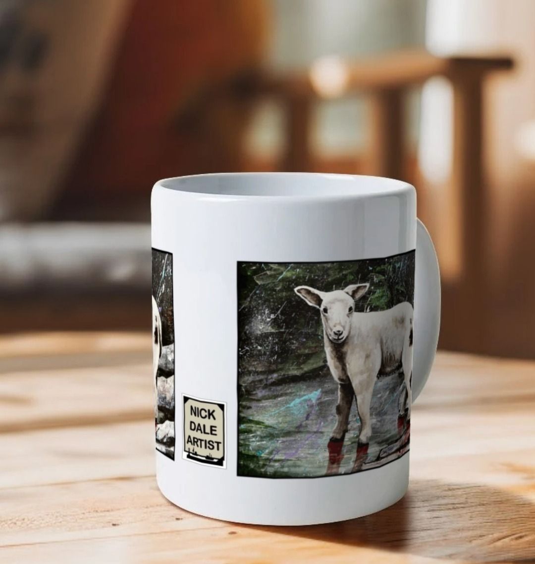 Image of a White Mug on a wooden table featuring a copy of the painting 'The Lamb of Lundy' by Nick Dale. Image also shows artist's logo on the mug. The mug handle is obscured behind the mug. The mug depicts a close-up study of a lamb observed on the island of Lundy, Devon.
