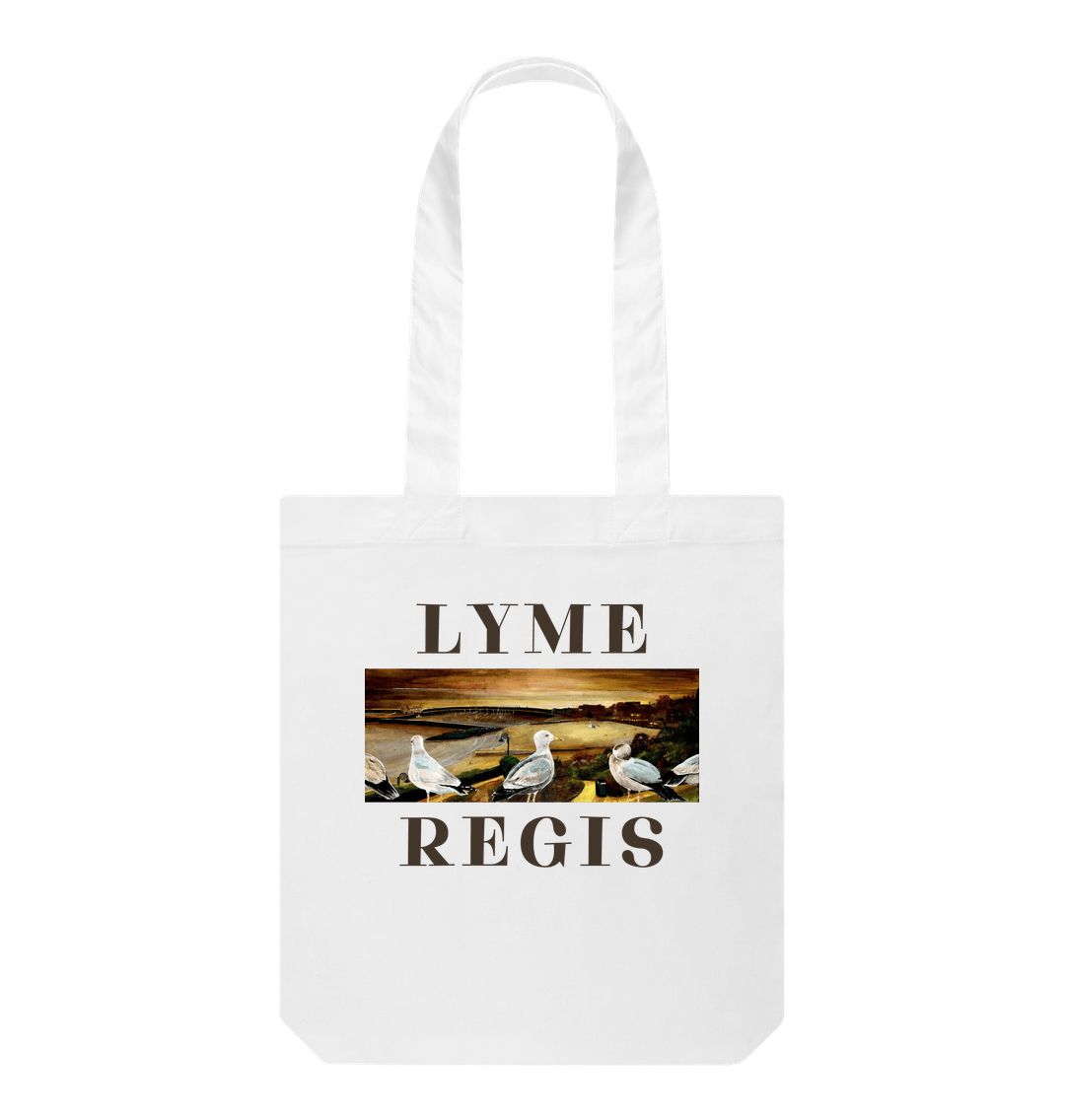 Image of a White Tote Bag featuring a copy of the painting 'The Flock Of Lyme Regis' by Nick Dale, with the word 'Lyme' written above it and the word 'Regis' written below it. The bag depicts a sunset view over the town and seafront, including the harbour and cobb at Lyme Regis, Dorset, from Langmoor Gardens.