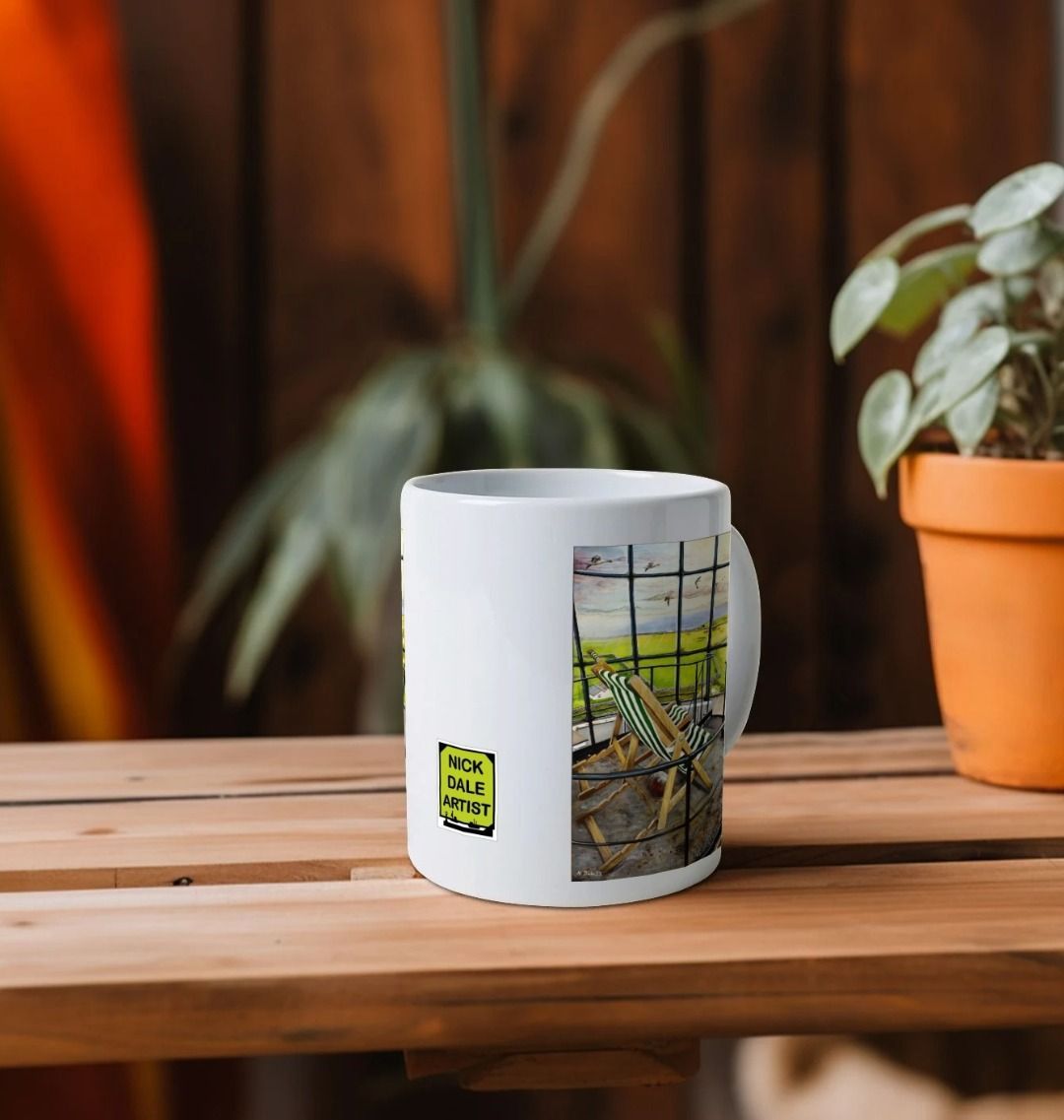Image of a White Mug on a wooden shelf featuring a copy of the painting 'Let's Be Together Alone' by Nick Dale. Image also shows artist's logo on the mug. The mug handle is obscured behind the mug. The mug depicts the view from the lantern room of the Old Light lighthouse on Beacon Hill, on the island of Lundy, Devon.