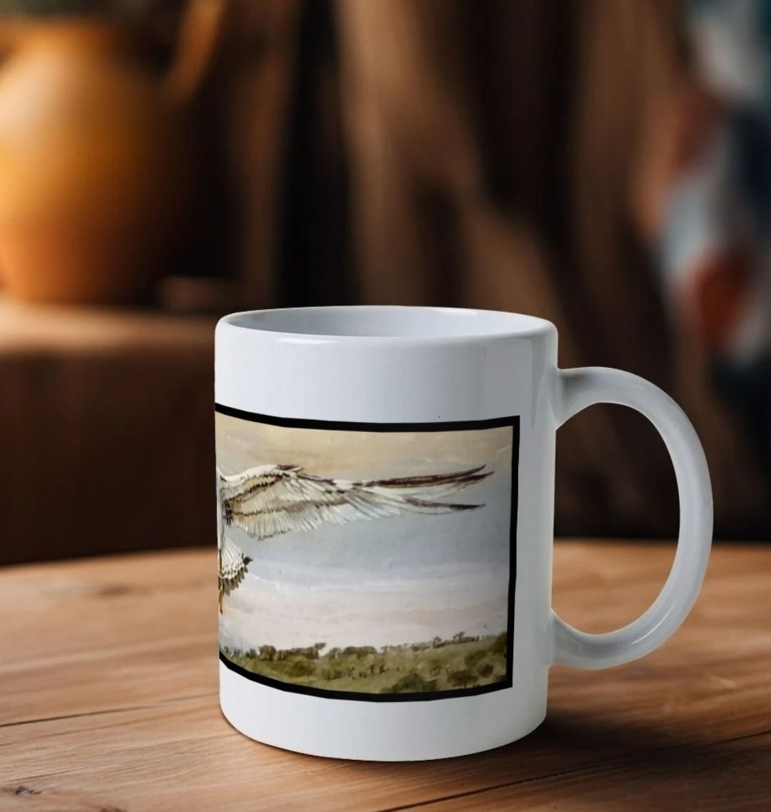 Image of a White Mug on a wooden table featuring a copy of a detail from the painting 'The Gordian Knot At Lyme Regis' by Nick Dale. The handle is orientated to the right. The mug depicts a gull flying over the Cobb at Lyme Regis, Dorset. The title refers to the jumbled pile of fishing equipment sitting on the quayside visible in the original painting.