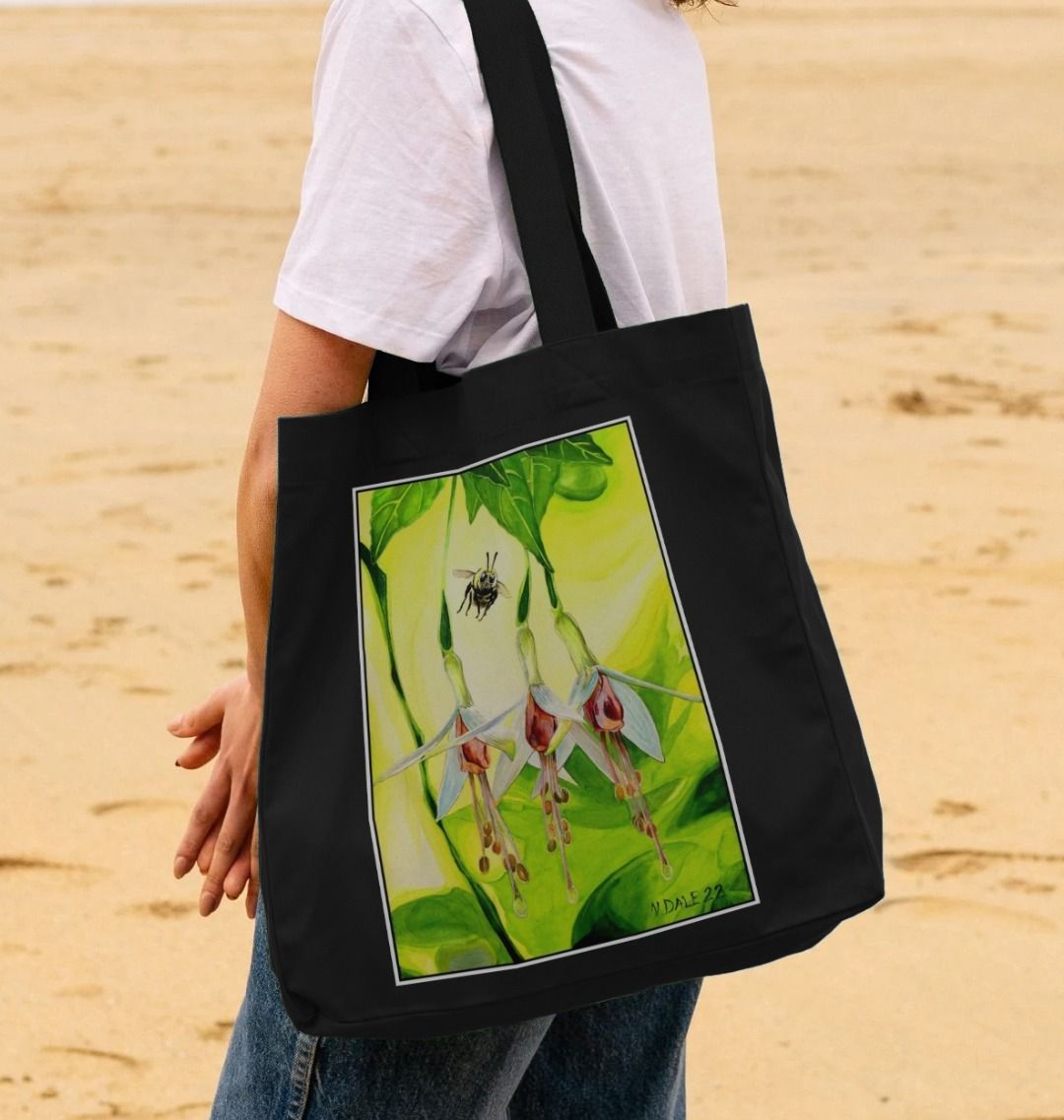 Image of a female model carrying a Black Shopper Tote Bag featuring a copy of the painting 'The Three Muses' by Nick Dale. The bag depicts a close-up view of a bee approaching its prize. But which will it choose?