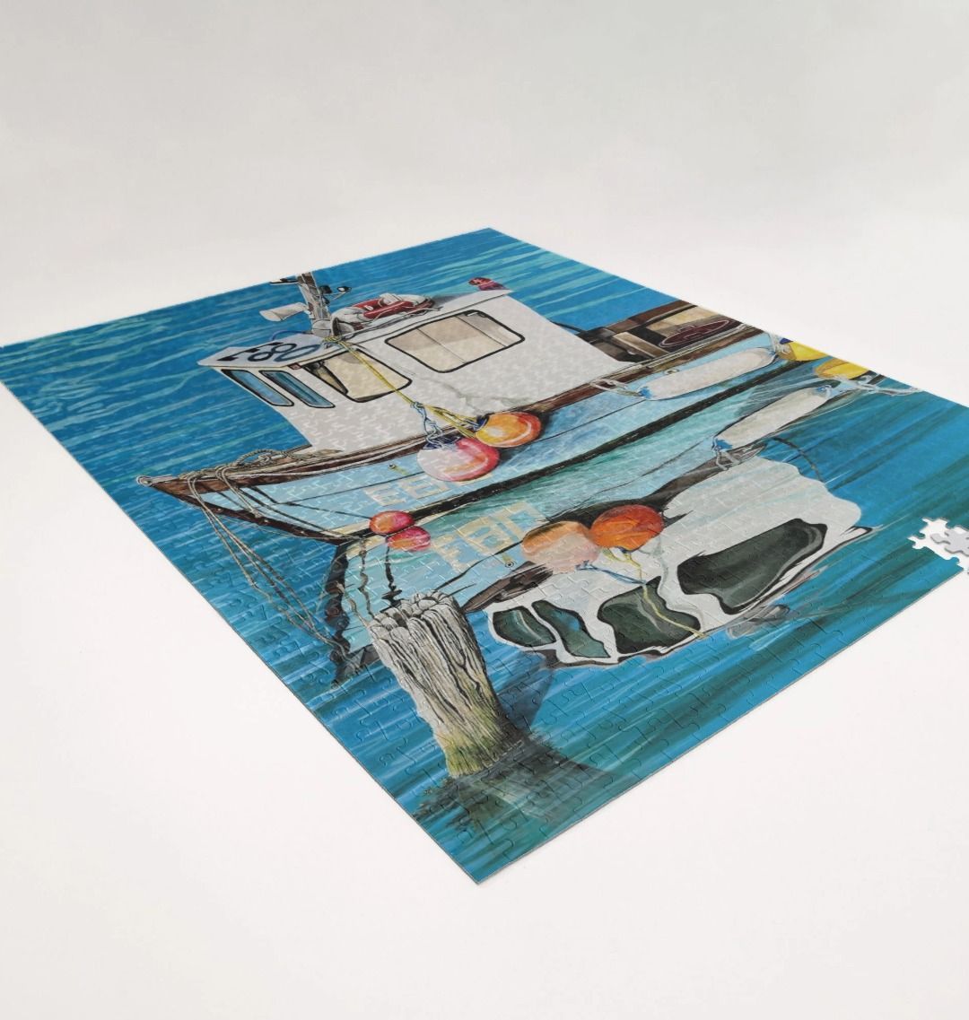 Image of a 1000 Piece Jigsaw Puzzle featuring a copy of the painting 'God's Own 99 Flake Pierces The Veil' by Nick Dale. As displayed partially completed on a white surface. The jigsaw depicts a fishing boat at rest within the harbour of Lyme Regis, Dorset. The title is based on the similarity of the wooden pile to a chocolate flake as inserted into an ice cream cone. This seemed appropriate given the draw of the town to tourists.