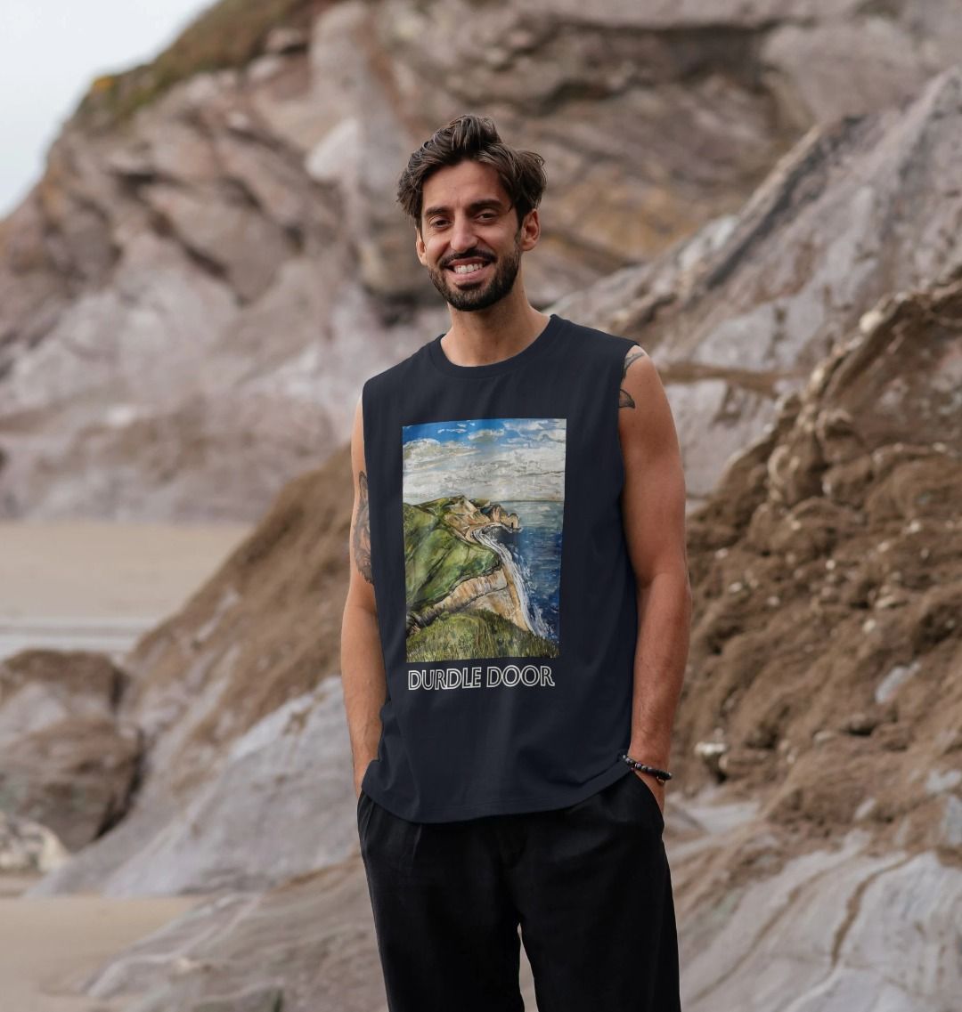 Image of a male model wearing a Navy Blue Men's Organic Cotton Vest featuring a copy of the painting 'Durdle Door From The West' by Nick Dale with the words 'Durdle Door' written below it. The vest depicts a view along the Jurassic Coast to the famous Dorset limestone arch landmark, as seen from the coastal path to the west.
