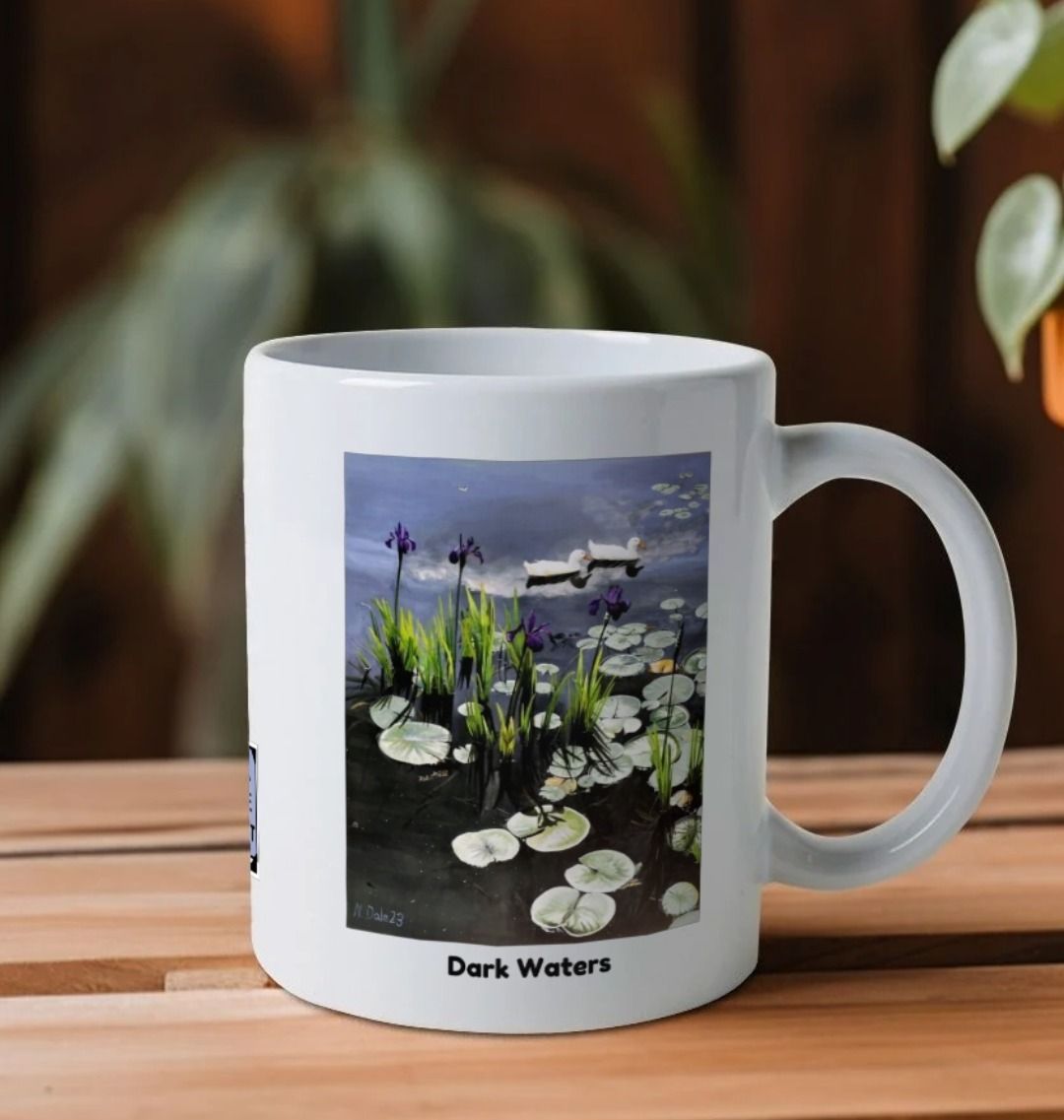 Image of a White Mug on a table featuring a copy of the painting 'Dark Waters' by Nick Dale, with the words 'Dark Waters' written beneath it. The handle is orientated to the right. The mug depicts lily pads, irises and ducks on a pond at Knightshayes Court, Devon.